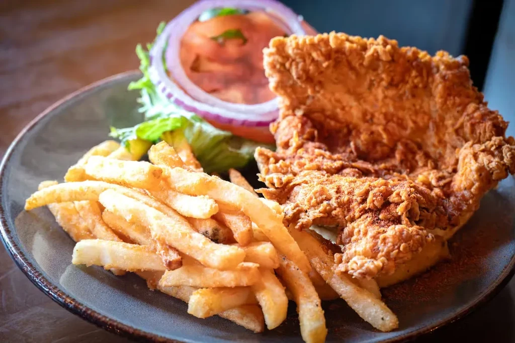 Crispy fried chicken, golden fries, and salad on a dark plate.