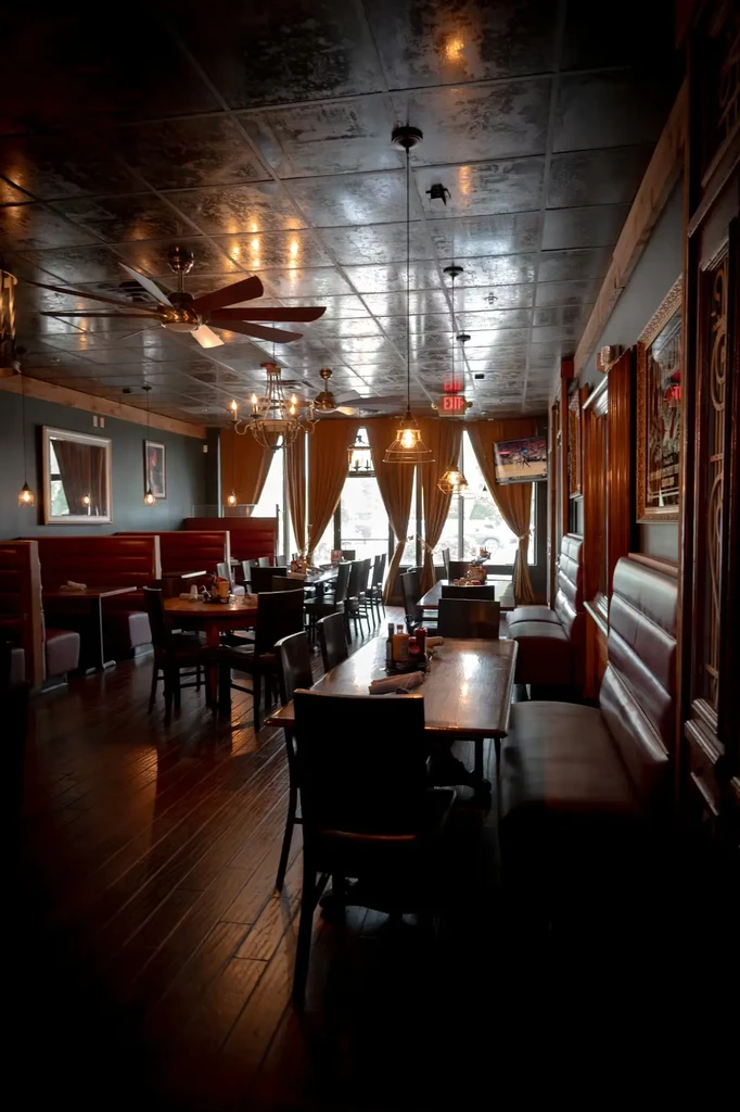Warm, dimly lit restaurant interior with dark wood, booths, and chandeliers.