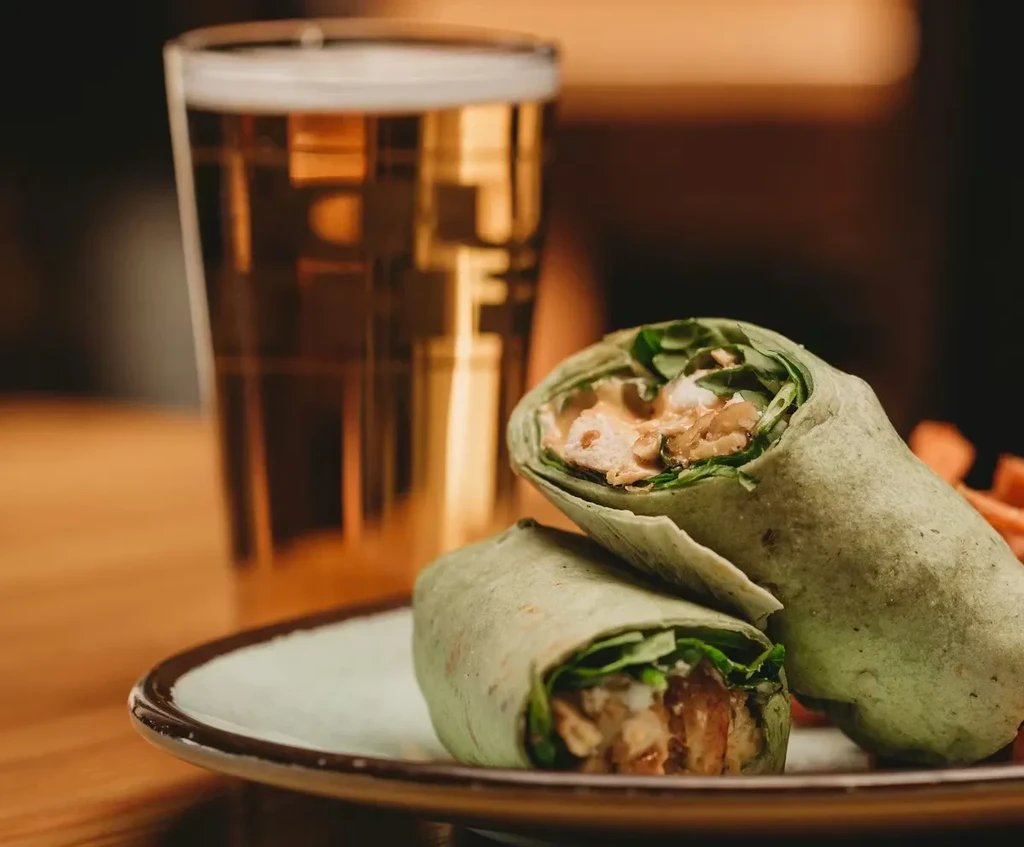Two green tortilla halves filled with chicken, vegetables, beer.