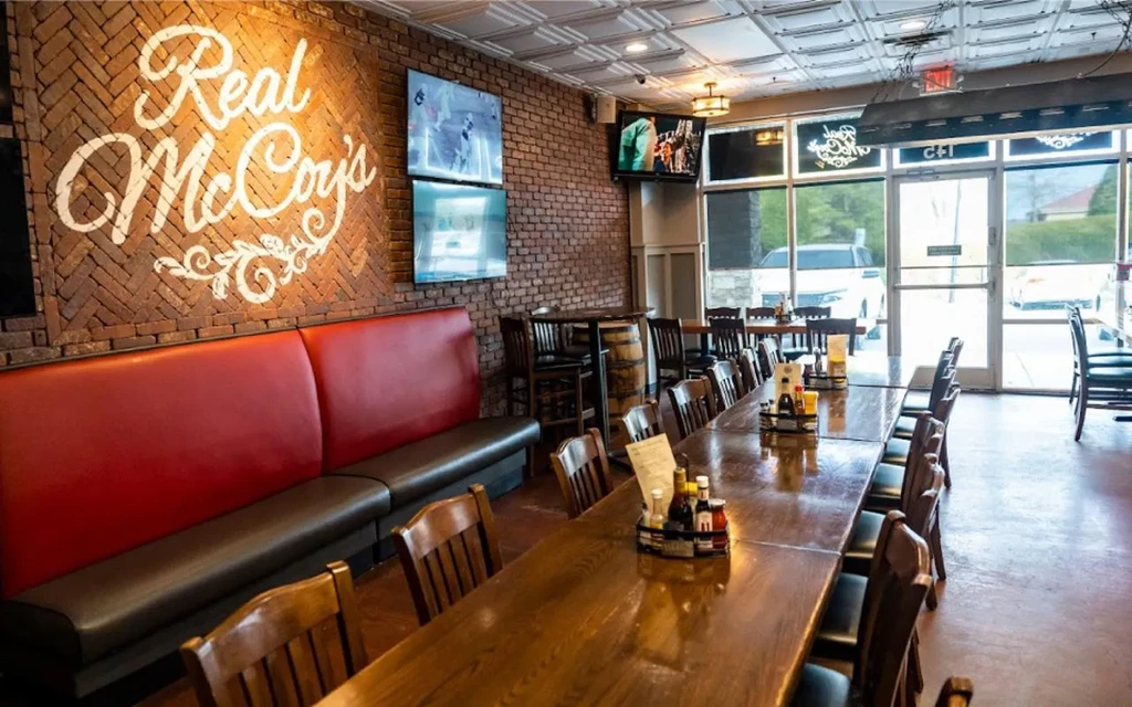 Real McCoy's restaurant interior with communal table, booth, and sports screens.