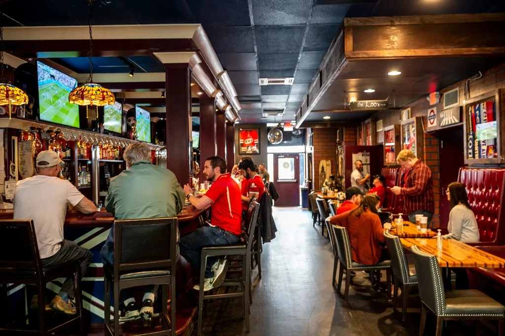 Bustling pub with Tiffany lamps, Union Jack stools, and sports memorabilia.