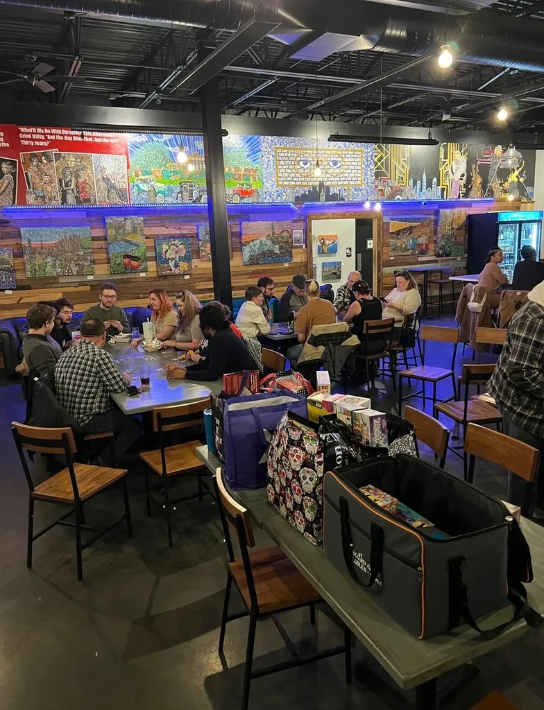Lively, industrial-chic restaurant with blue LEDs, colorful art, and patrons.