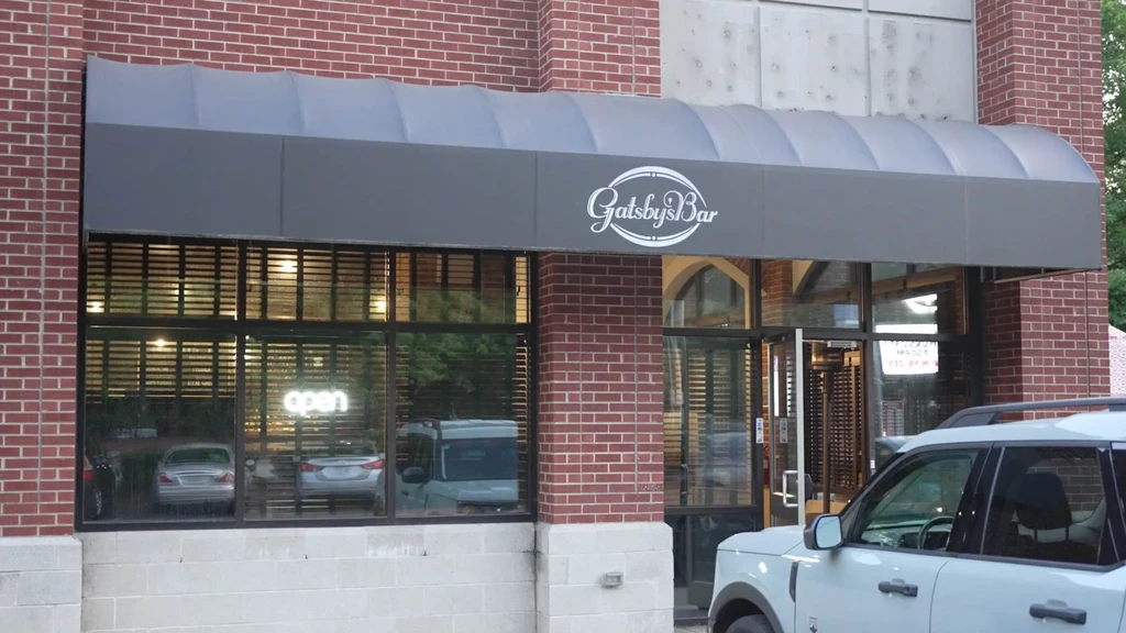 Exterior of Gatsby's Bar with red bricks and grey awning.