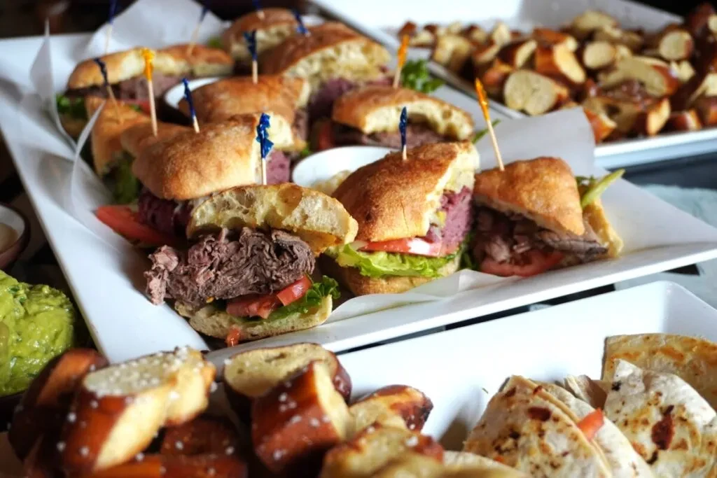White platter with gourmet sandwiches, pretzel bites, and other appetizers.