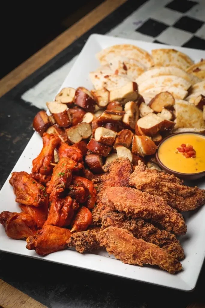 Appetizer platter with buffalo wings, fried chicken, pretzels, cheese dip.