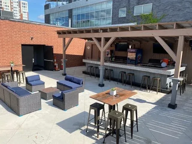Bright outdoor bar patio with diverse seating and city buildings.