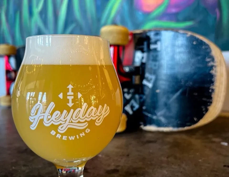Foamy Heyday Brewing beer in a tulip glass, with a skateboard and mural.