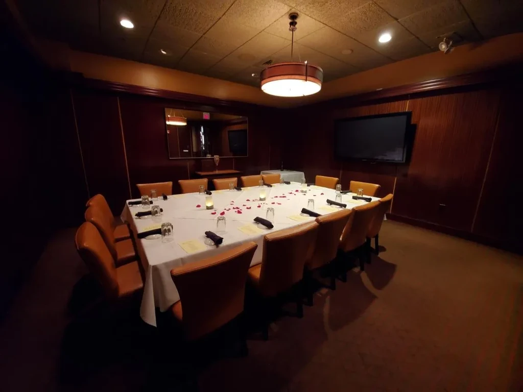 Elegant private dining room with a long, candlelit table decorated with roses.