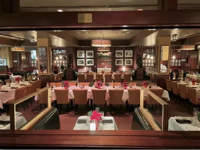 Elegantly set restaurant dining room with red flowers and warm lighting.