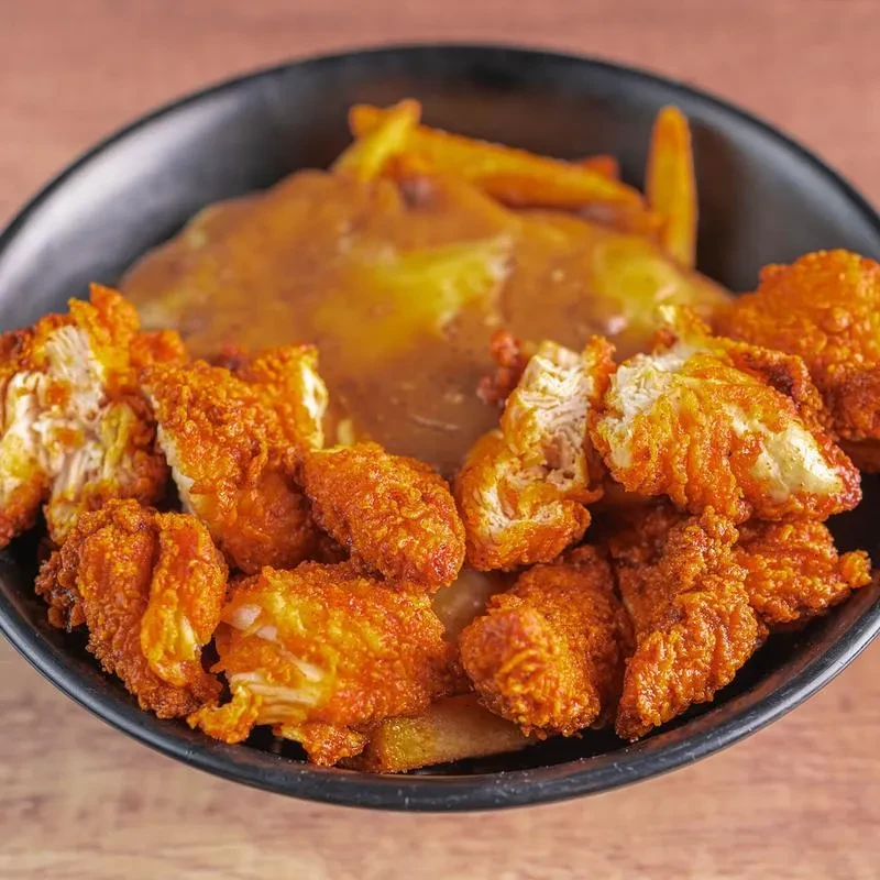 Crispy fried chicken, French fries, and gravy in a black bowl.