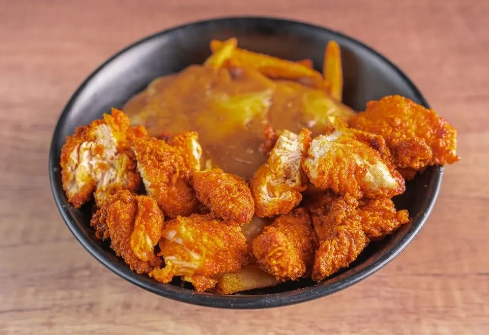 Close-up of fried chicken and fries smothered in brown gravy.