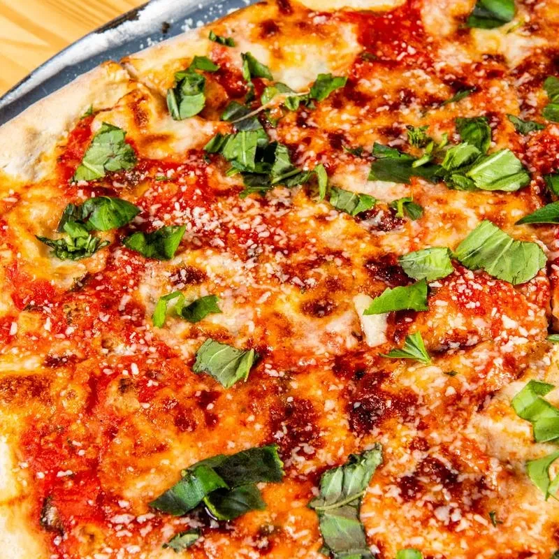 Freshly baked pizza with red sauce, white cheese, and green basil.