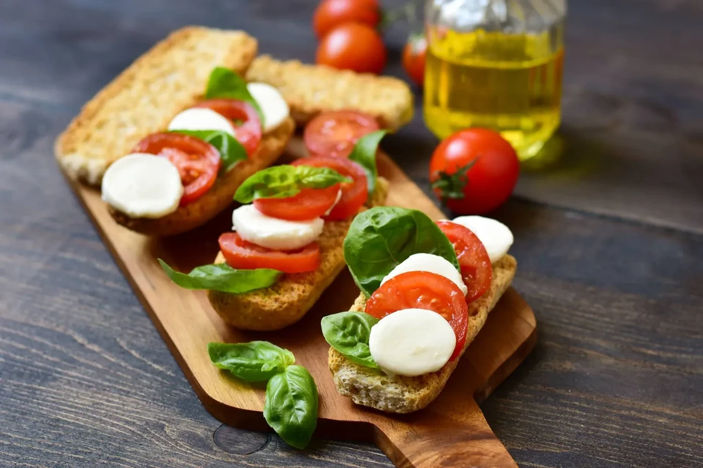 Bruschetta with tomato, mozzarella, basil on wooden board; olive oil.