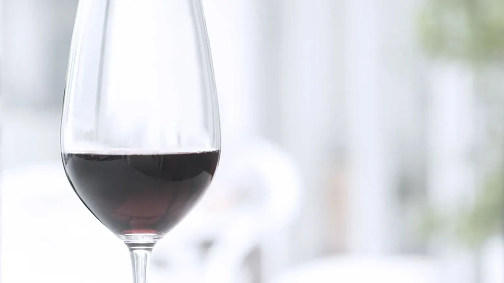 Close-up of a red wine glass with a blurred, light background.