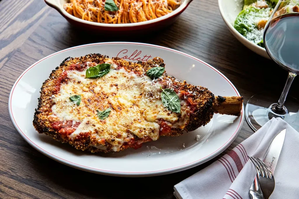 Breaded cutlet with melted mozzarella, tomato sauce, and basil on a dinner table.