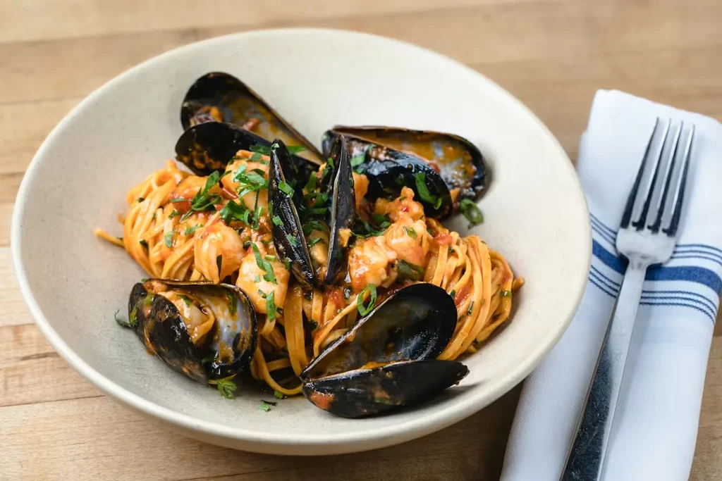 Seafood pasta with mussels and red sauce in a rustic bowl.
