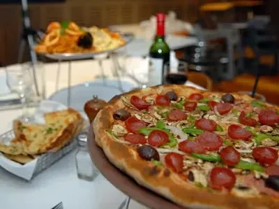 Close-up of pizza with pepperoni, mushrooms, peppers, olives, garlic bread.