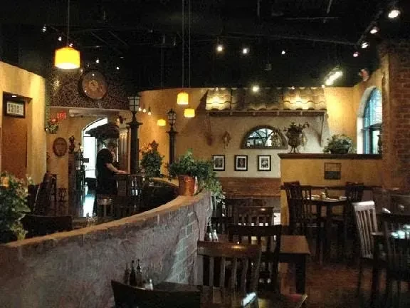Warm-lit rustic restaurant interior with wooden tables and exposed brick.