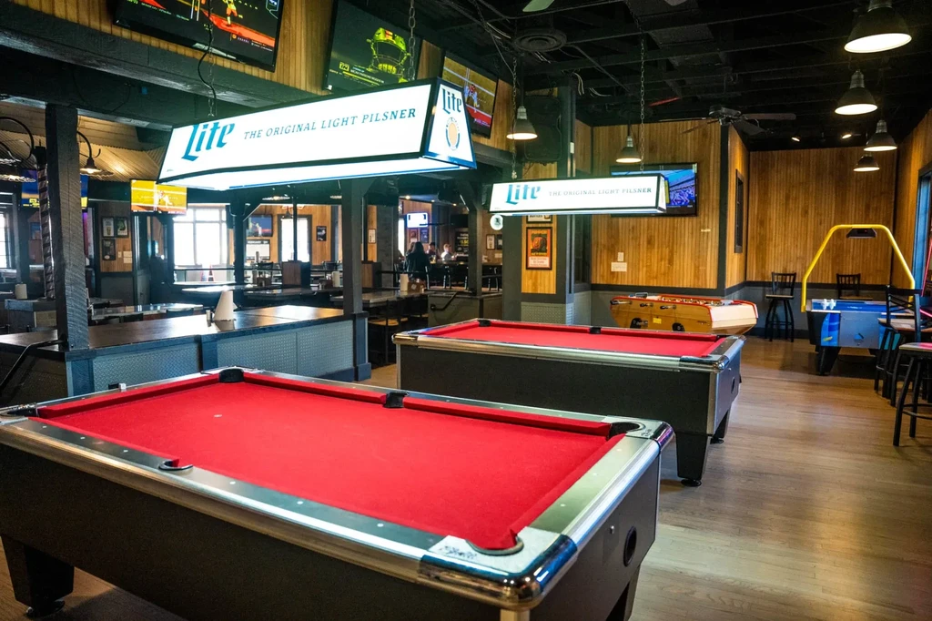 Sports bar with two pool tables, other games, and multiple TVs.