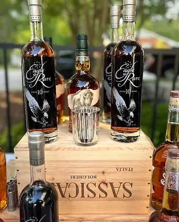 Multiple whiskey bottles, prominently Eagle Rare, arranged on a wooden wine crate.