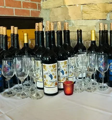 Wine bottles, empty glasses, and glowing candle against a rustic wall.