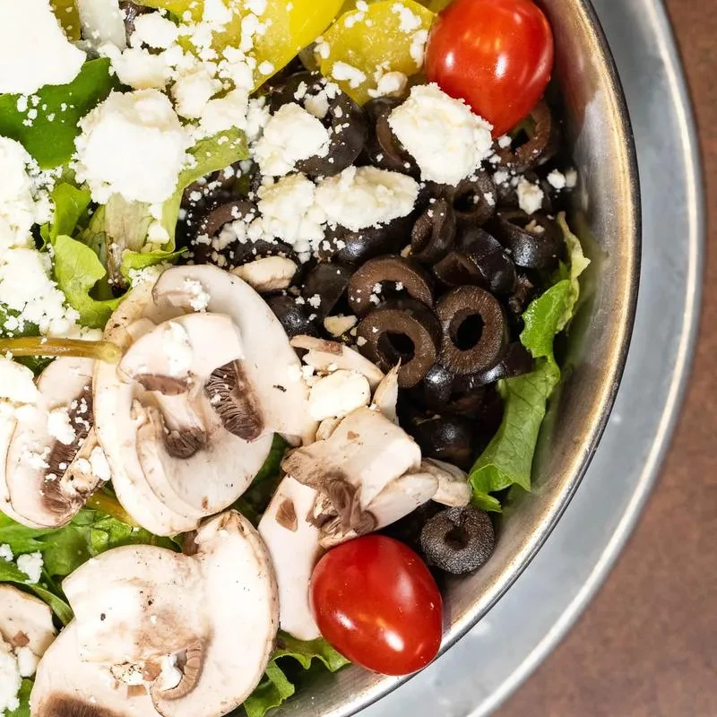 Vibrant mixed salad with lettuce, mushrooms, olives, feta, cherry tomatoes.