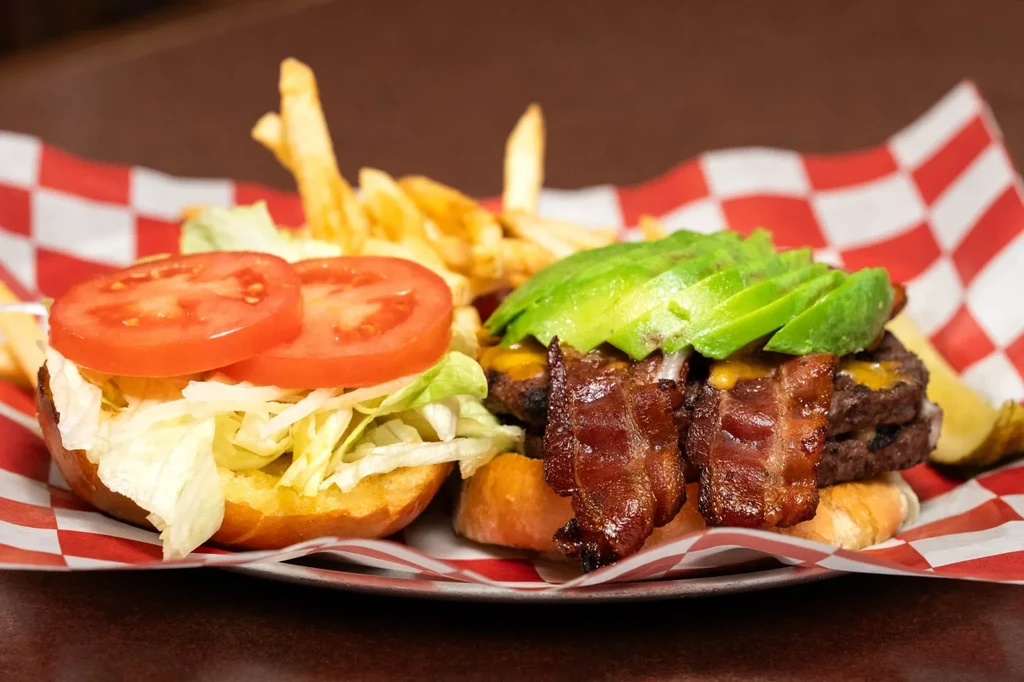 Double-patty burger with cheese, bacon, avocado, and fries.