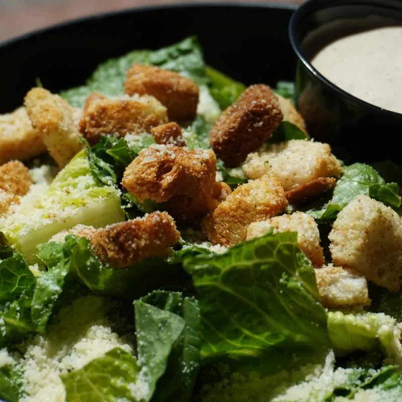 Top-down Caesar salad with romaine, croutons, cheese, and dressing.