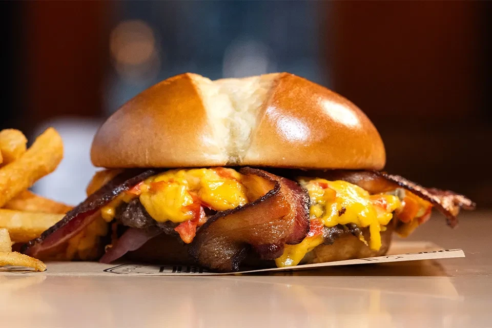 Gourmet burger with melted cheese, bacon, and golden french fries.