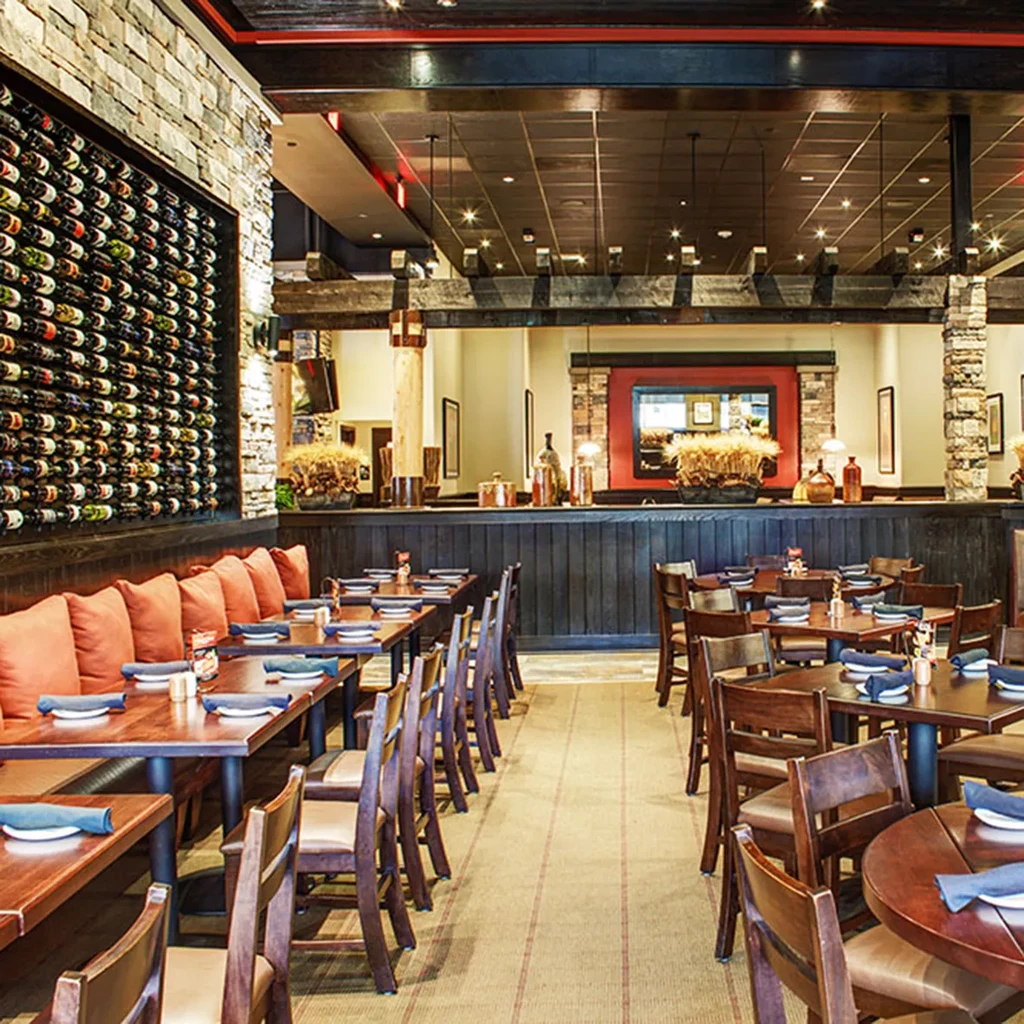 Empty restaurant dining area with tables, stone wine rack, and bar.