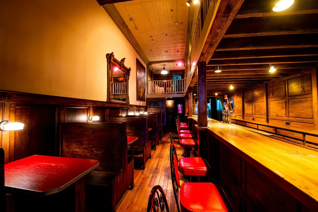 Cozy, rustic bar and restaurant interior with dark wood and red seating.