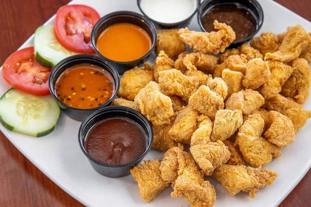 Fried chicken nuggets, tomatoes, cucumbers, and five dipping sauces.