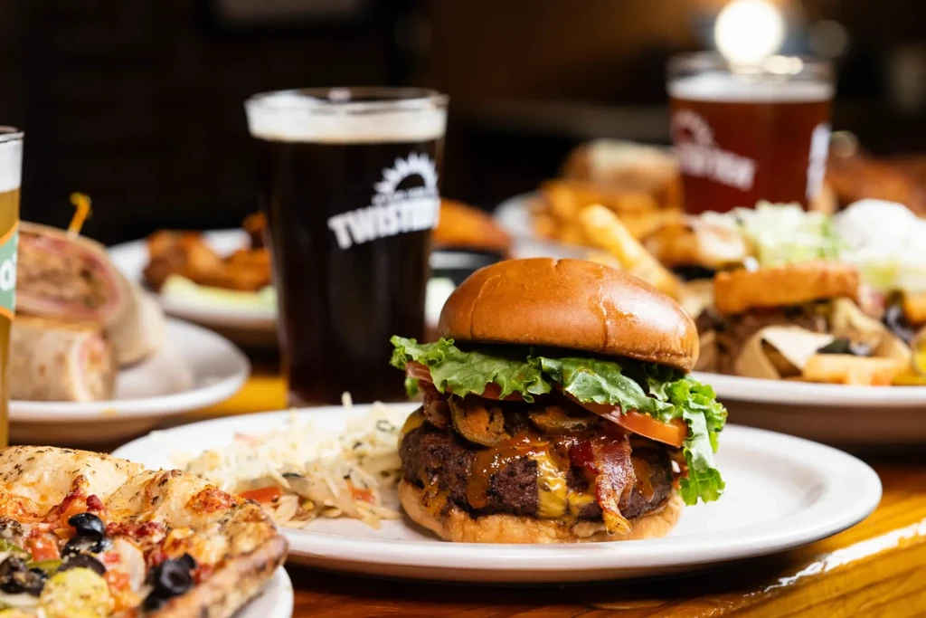 Burger with bacon, cheese, coleslaw, and a glass of dark beer.