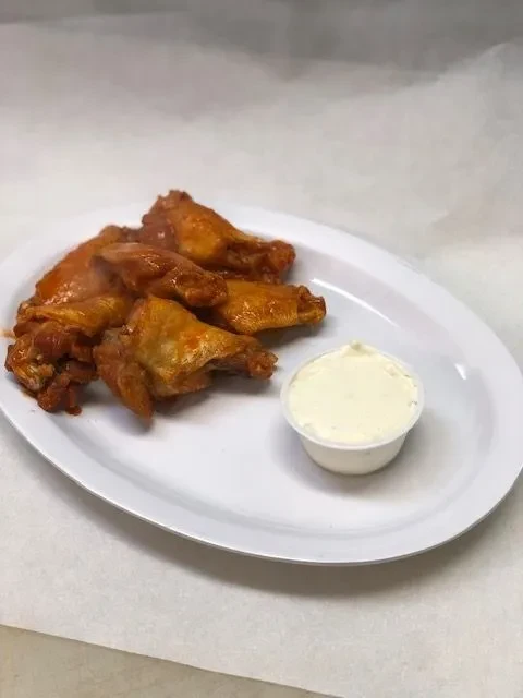Six steaming buffalo chicken wings with white dipping sauce.