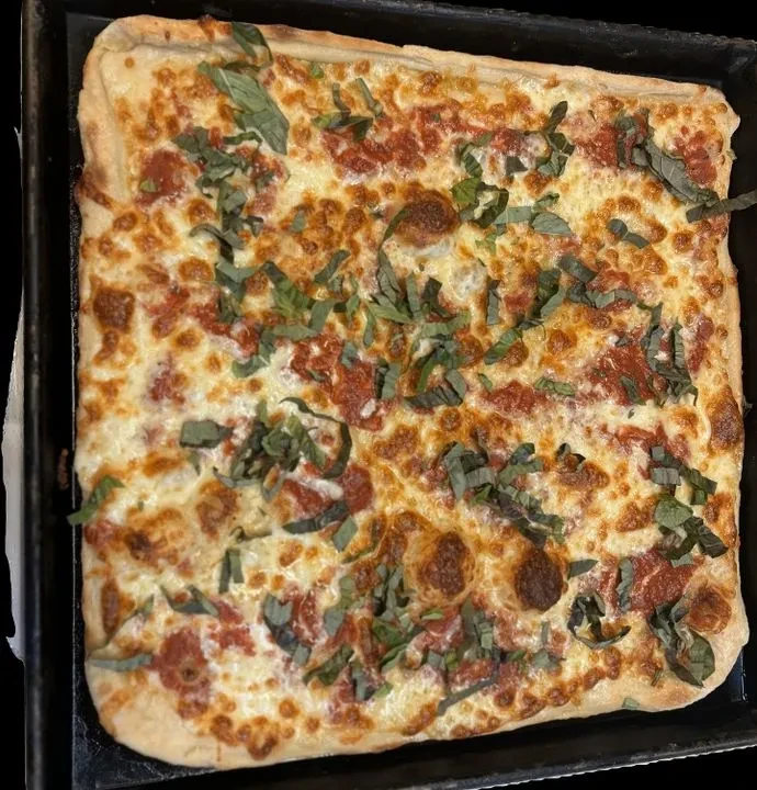 Square pizza with melted cheese, tomato sauce, and fresh basil.