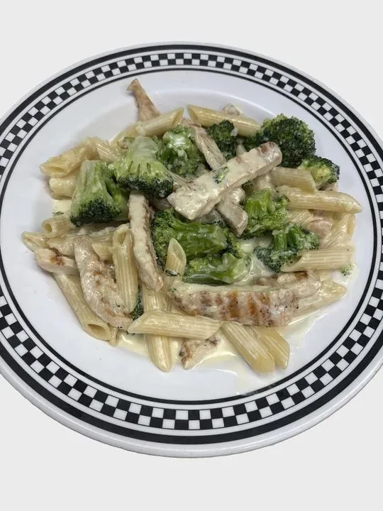 Creamy penne pasta with grilled chicken and vibrant green broccoli.