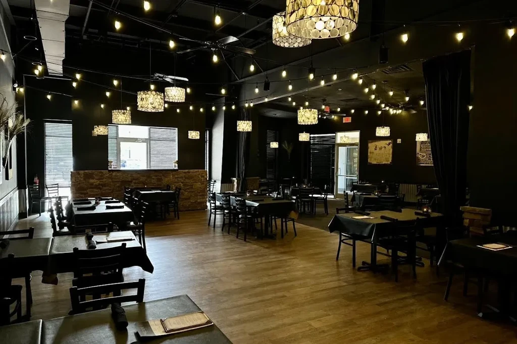 Dark restaurant interior with string lights, pendant lamps, and many tables.