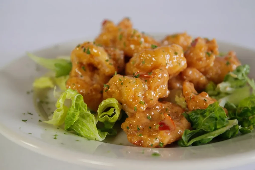 Golden-brown battered shrimp with creamy orange sauce and lettuce.