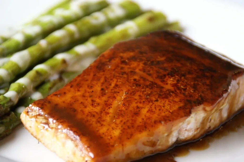 Pan-seared salmon with a glossy amber glaze and green asparagus.