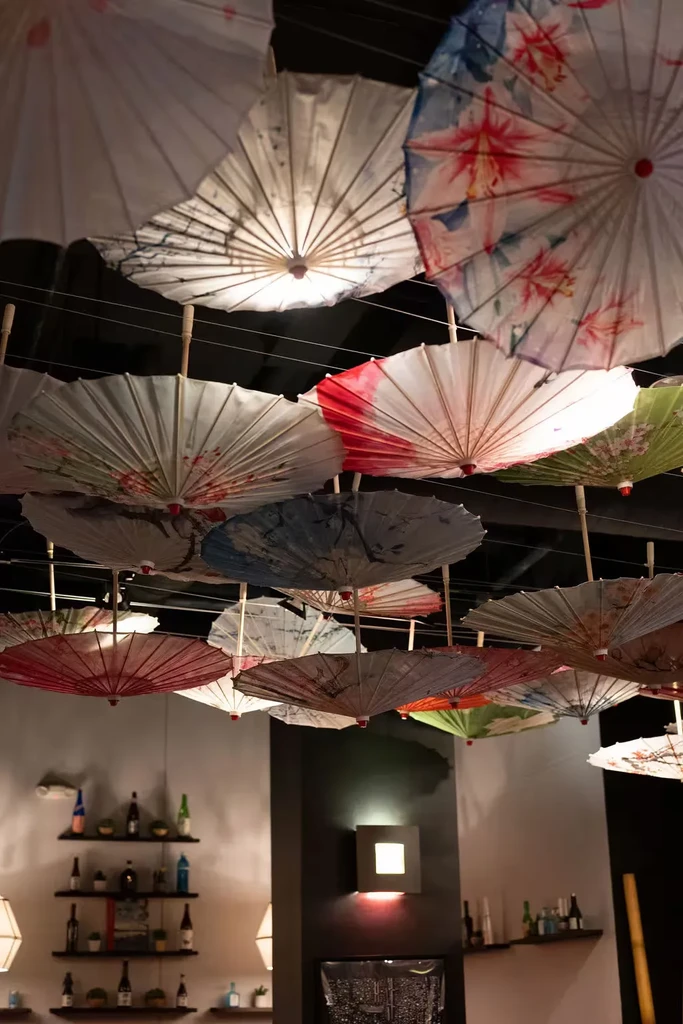 Colorful, lit Japanese paper umbrellas adorn a dim restaurant ceiling.