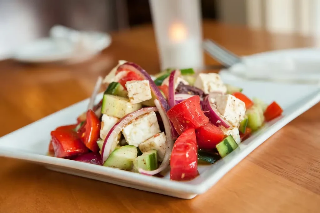 Plated Greek salad with tomatoes, feta, cucumbers, and red onions.
