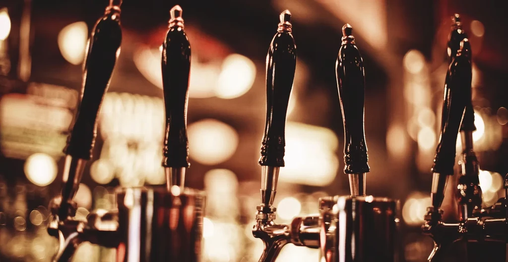 Close-up of five elegant beer taps in a dimly lit bar.