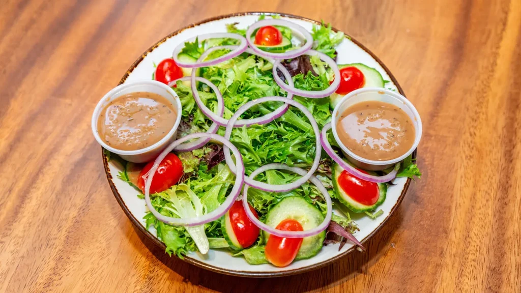 Fresh garden salad with lettuce, tomatoes, cucumbers, onions, and dressing.