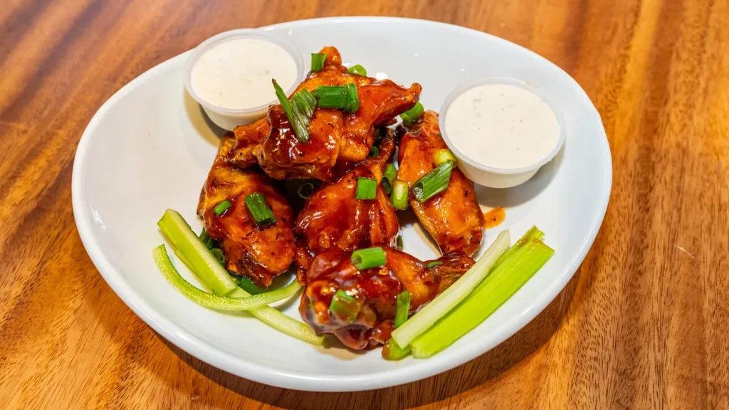 Chicken wings in dark red sauce, celery, cucumber, and two dips.