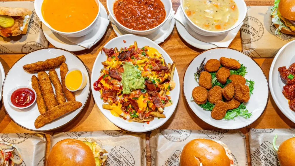Overhead view of diverse comfort food: soups, loaded fries, burgers.