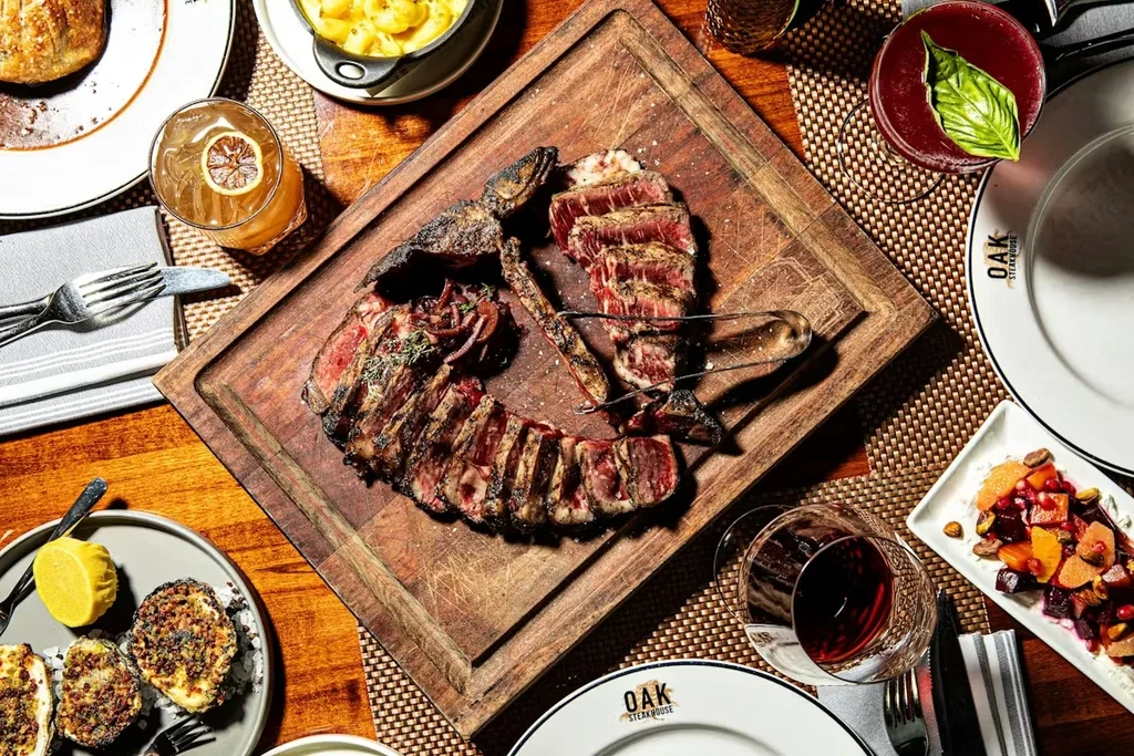 Overhead: Steak on rustic board, mac and cheese, salad, cocktails.