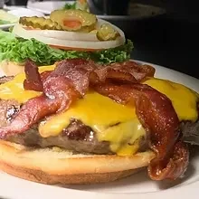 Open-faced cheeseburger, patty, cheese, bacon, lettuce, tomato, onion, pickles.
