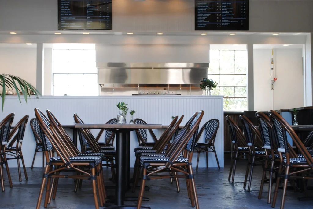 Spacious, modern restaurant interior with stacked chairs, open kitchen, and menu boards.