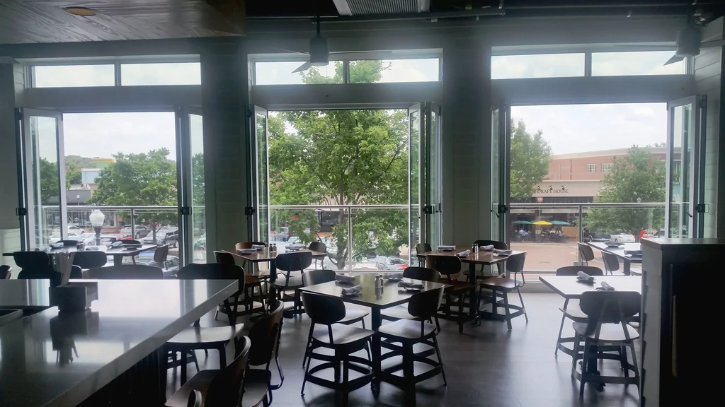 Modern empty restaurant interior with panoramic view through large glass doors.