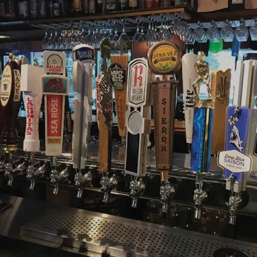 Numerous distinct beer tap handles showing various brewery logos.